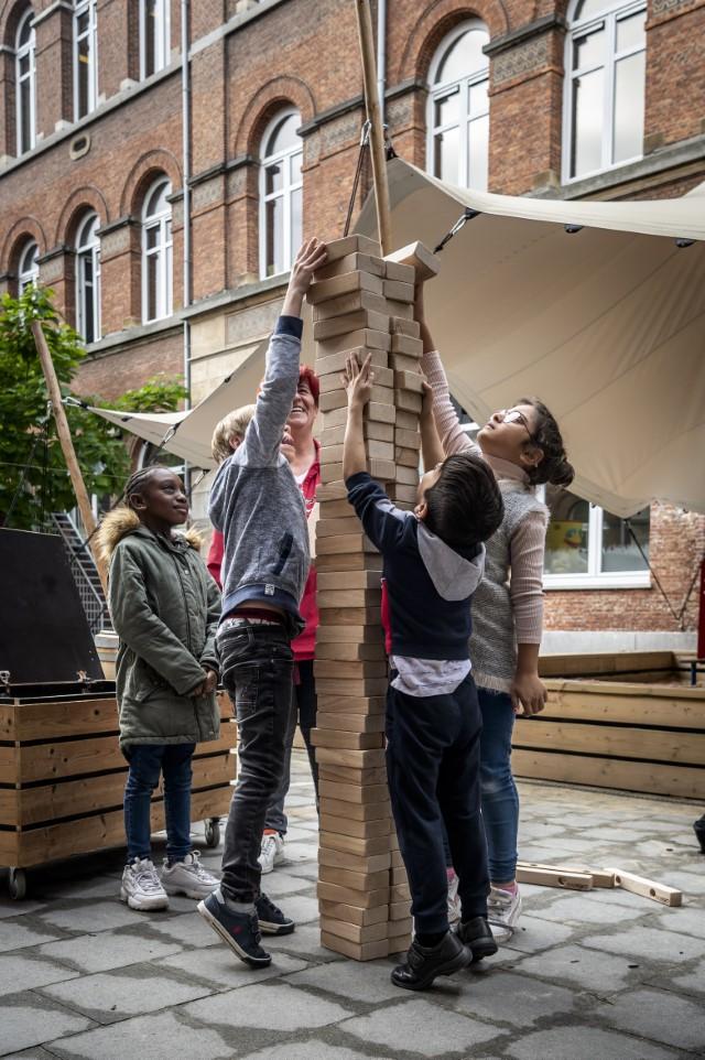 Leerlingen bouwen samen een reuzegrote toren op de speelplaats van Leerexpert De Novanaut